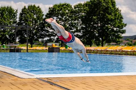 Ein Mann springt in das Sportbecken.